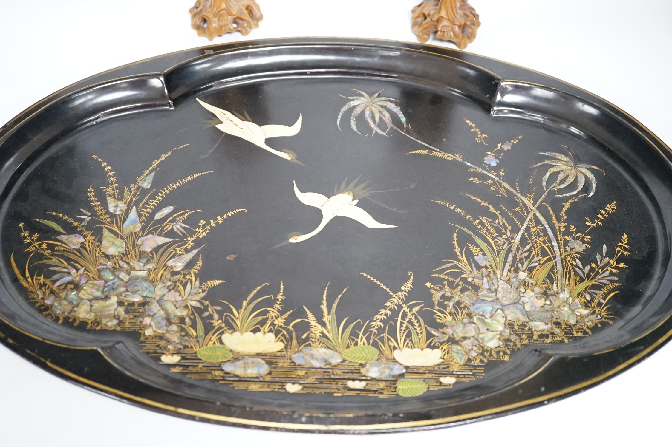 An oval japanned toleware tray and a pair of Chinese carved wood figures, largest 61cm wide